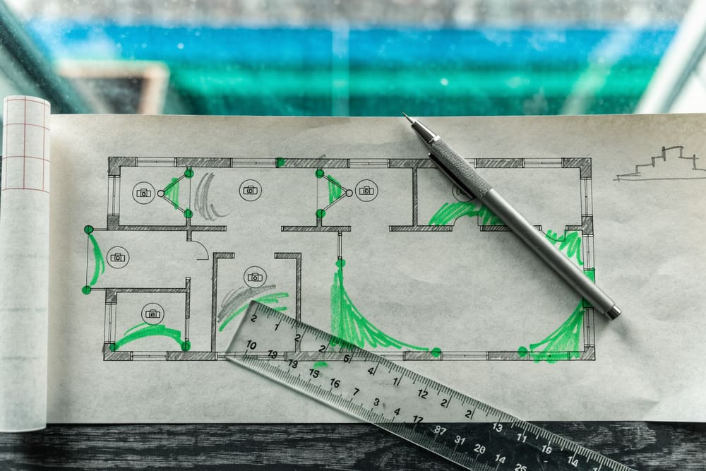 A floor plan with camera positions and coverage arcs marked in pencil and highlighter, ruler alongside.